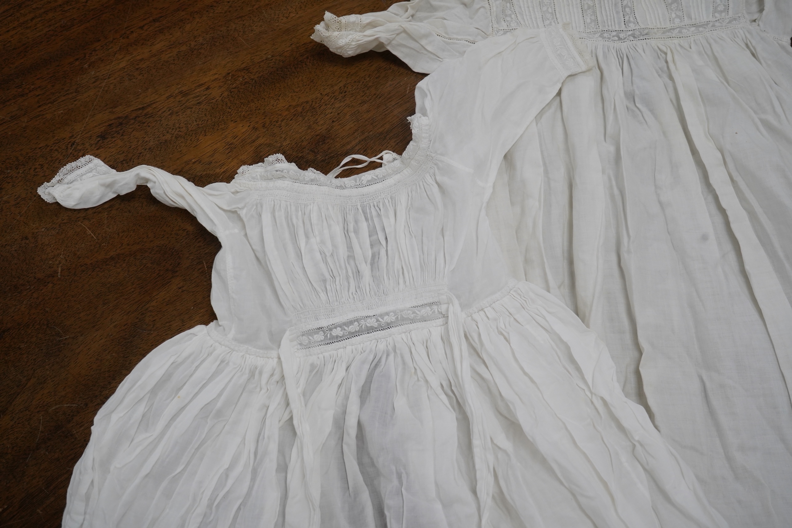 Two late 19th early 20th century long baby night gowns and two shorter baby gowns, together with a pink satin ladies full length slip and a similar cream silk stockinette slip, the bodices worked on baby dresses are embr